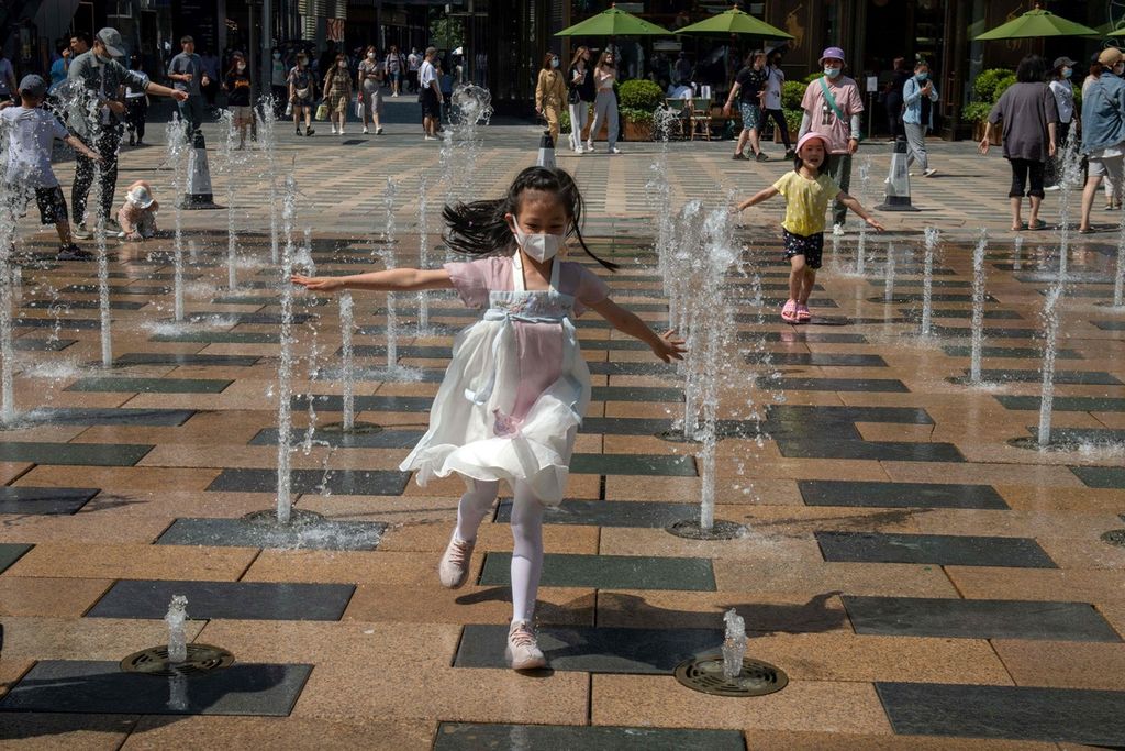 Seorang anak perempuan bermain di dekat air mancur di luar sebuah pusat perbelanjaan di Beijing, China, pada Hari Anak Internasional, 1 Juni 2021. 