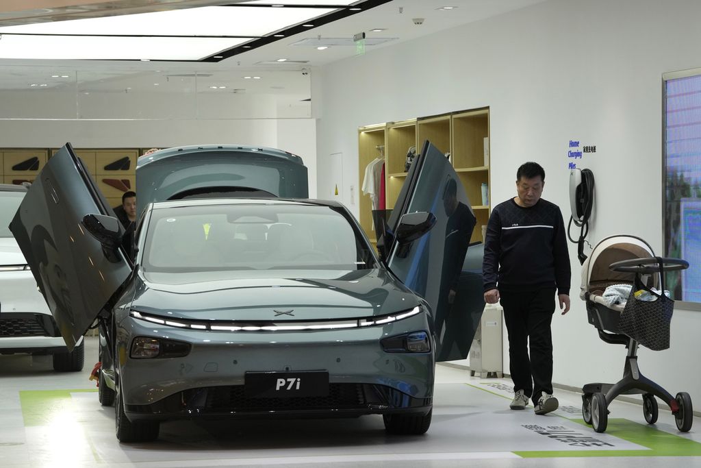 Seorang pengunjung berjalan di dekat sedan listrik P7i dari pembuat mobil China Xpeng di ruang pamer di Beijing, Kamis (13/4/2023). 