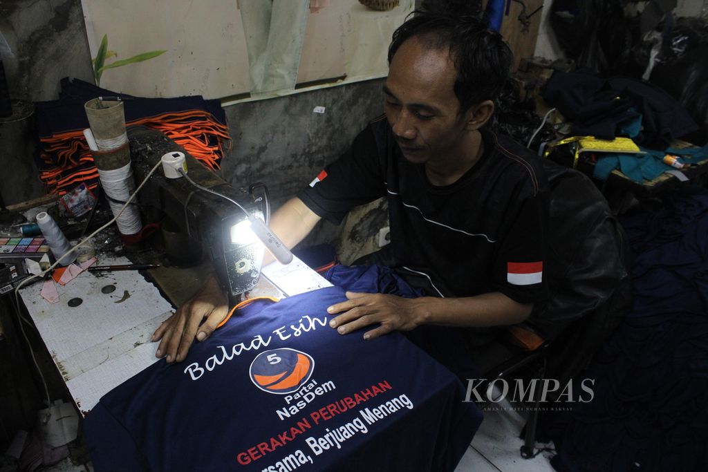 Seorang penjahit menyelesaikan pekerjaan kaus salah satu partai di Kecamatan Cibeunying Kaler, Kota Bandung, Jawa Barat, Selasa (17/10/2023). Meskipun tahun politik mulai menjelang, pesanan kaus partai masih belum menunjukkan peningkatan.