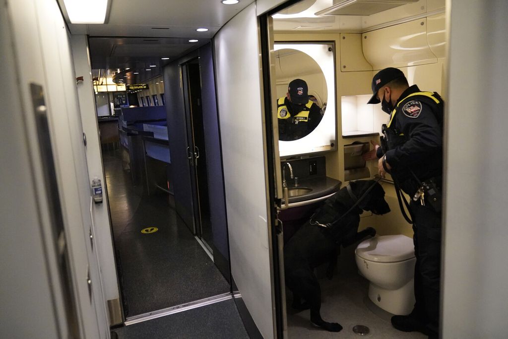 Seorang personil Kepolisian dan anjing pelacak memeriksa toilet di kereta Amtrak sebelum keberangkatan dari Staasiun Union seiring peningkatan status keamanan menjelang upacara pelantikan Presiden terpilih Joe Biden di Washington, Selasa (19/1/2021).  