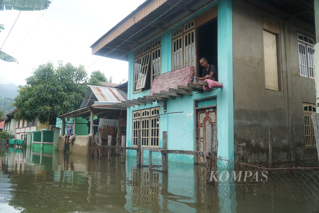 Warga sedang duduk di lantai dua rumahnya karena lantai dasar rumah terendam banjir akibat meluapnya Danau Kerinci di Desa Pulau Tengah, Kecamatan Keliling Danau, Kabupaten Kerinci, Jambi, Selasa (16/1/2024). 