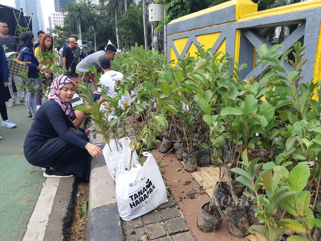 Sejumlah warga mengambil bibit tanaman gratis di momen hari bebas kendaraan bermotor di ruas Jalan Sudirman-Thamrin, Jakarta, Minggu (18/2/2024).