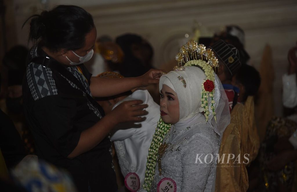 A family is fixing the makeup of a bride during a mass wedding confirmation ceremony at Empire Palace in Surabaya, East Java on Tuesday (30/8).