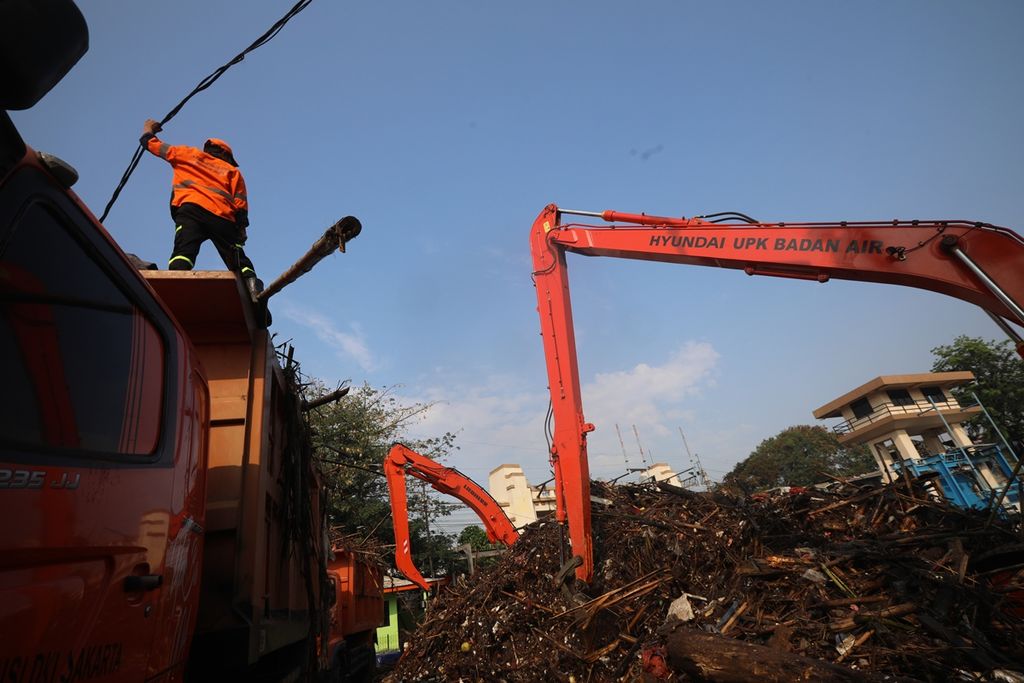 Alat berat Unit Pelaksana Kebersihan Badan Air DKI Jakarta memindahkan tumpukan berbagai sampah seperti batang pohon, bambu, styrofoam dan plastik, serta berbagai sampah rumah tangga keatas bak truk di Pintu Air Manggarai, Jakarta Selatan, Rabu (9/10/2019).