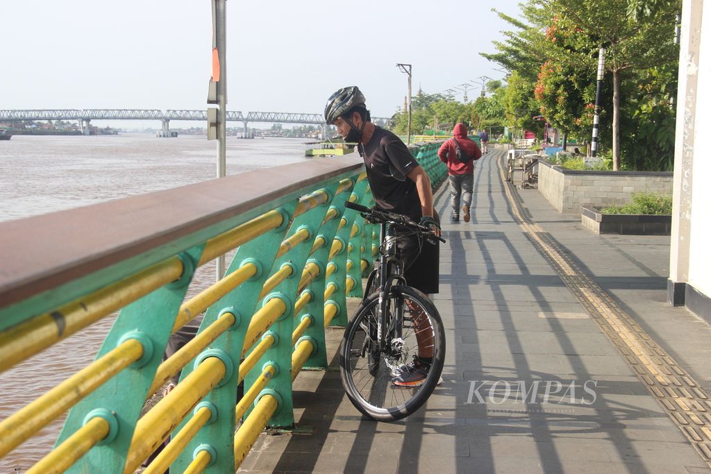 Warga bersepeda sekaligus menikmati suasana di tepian Sungai Kapuas, Kota Pontianak, Kalimantan Barat, Minggu (14/7/2024).