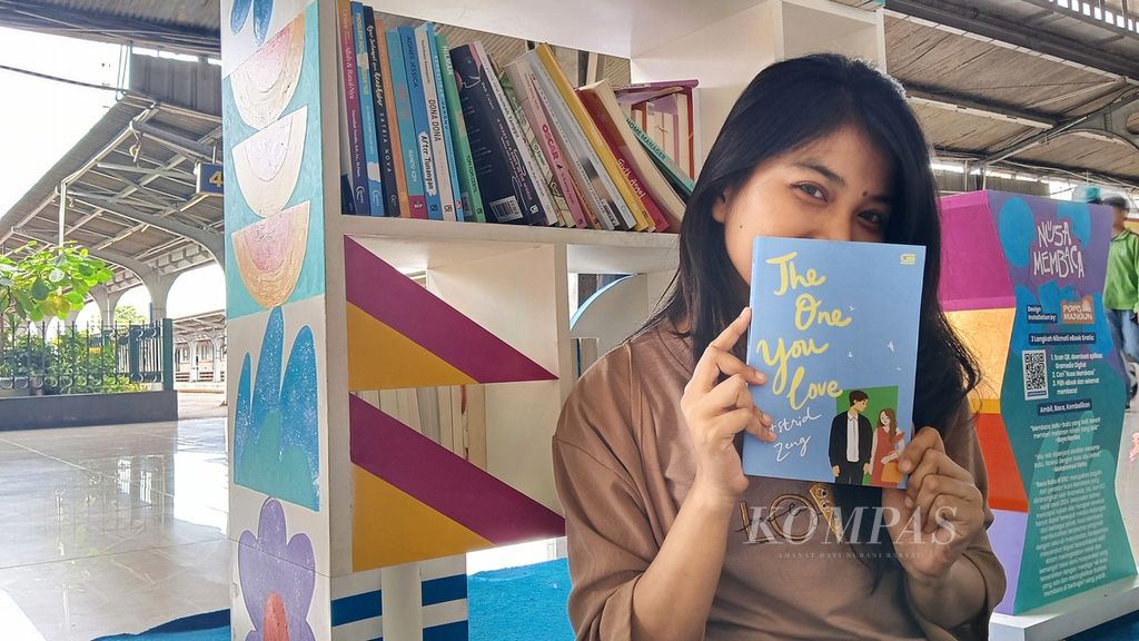 Wulandini (22), warga Mangga Dua, Jakarta Pusat, menunjukkan buku bacanya di perpustakaan mini Gramedia, Stasiun Jakarta Kota, untuk mengisi waktu luang.