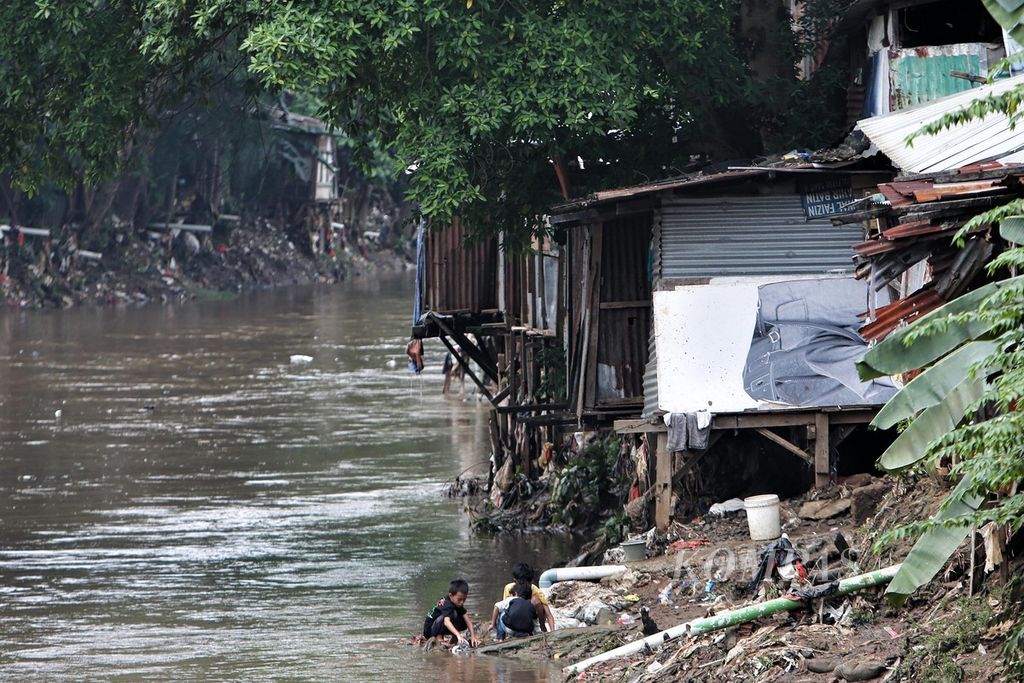 Anak-anak bermain di samping rumah semipermanen yang berdiri di atas bantaran Sungai Ciliwung, Manggarai, Jakarta Selatan, Minggu (17/7/2022). Badan Pusat Statistik mencatat, pada Maret 2022, angka kemiskinan 9,54 persen dari total penduduk atau sebanyak 26,12 juta orang, turun 0,17 persen dibandingkan September 2021, yakni 26,50 juta orang.