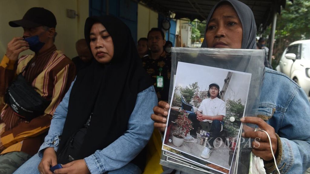 Rini Hanifah (43) memegang foto anaknya, Agus Rainsyah, yang menjadi korban dalam Tragedi Kanjuruhan dalam sidang perdana kasus Tragedi Kanjuruhan di Pengadilan Negeri Surabaya, Jawa Timur, Senin (16/1/2023). Sidang dilakukan secara daring dengan diikuti para terdakwa dari dalam Rutan Polda Jatim. 
