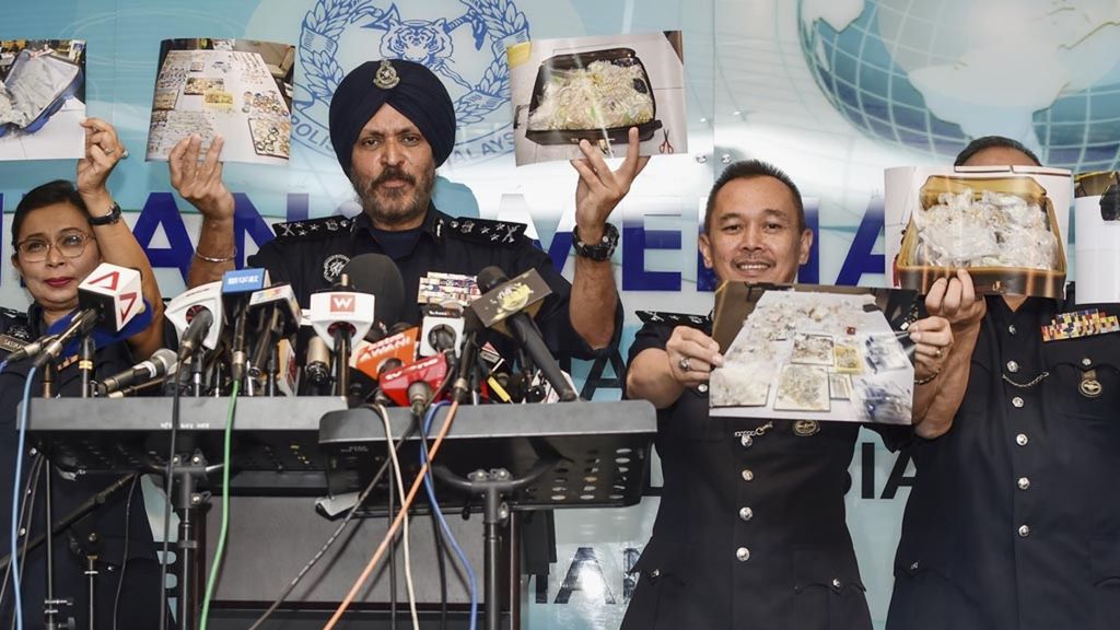 Para anggota kepolisian Malaysia, Rabu (27/6/2018), dalam jumpa pers di Kuala Lumpur, memegang foto barang-barang yang disita. Petugas menyita uang tunai dan berbagai benda berharga total senilai 275 juta dollar AS di sejumlah tempat terkait mantan Perdana Menteri Malaysia Najib Razak.