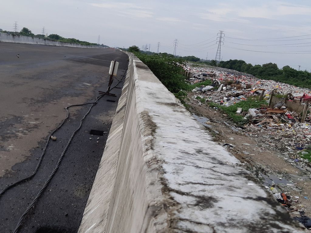Kondisi tumpukan sampah yang diapit proyek Tol Cibitung Cilincing dan Kali Cikarang Bekasi Laut di Desa Sumberjaya, Tambun Selatan, Kabupaten Bekasi, Selasa (25/1/2022) sore.