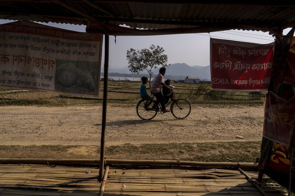 Seorang petani bersama dua anaknya melaju dengan sepeda mereka di kawasan pertanian Mikir Bamuni, Negara Bagian Assam, India,  18 Februari 2022. Gelombang panas menghantam sejumlah kawasan di India, antara lain mengakibatkan tanaman petani dilaporkan mati karena kekurangan air. 
