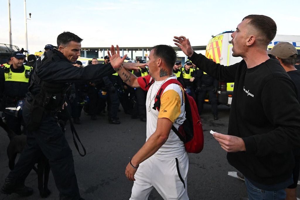 Aparat kepolisian menghalau seorang pengunjuk rasa dalam demonstrasi kelompok sayap kanan di Weymouth, Inggris, Minggu (4/8/2024). 