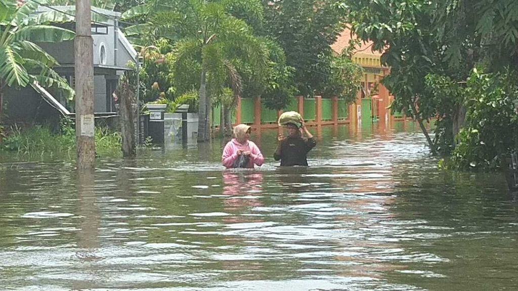 Warga melintasi banjir di Kelurahan Trimulyo, Kecamatan Genuk, Kota Semarang, Provinsi Jawa Tengah, Jumat (15/3/2024) sore.
