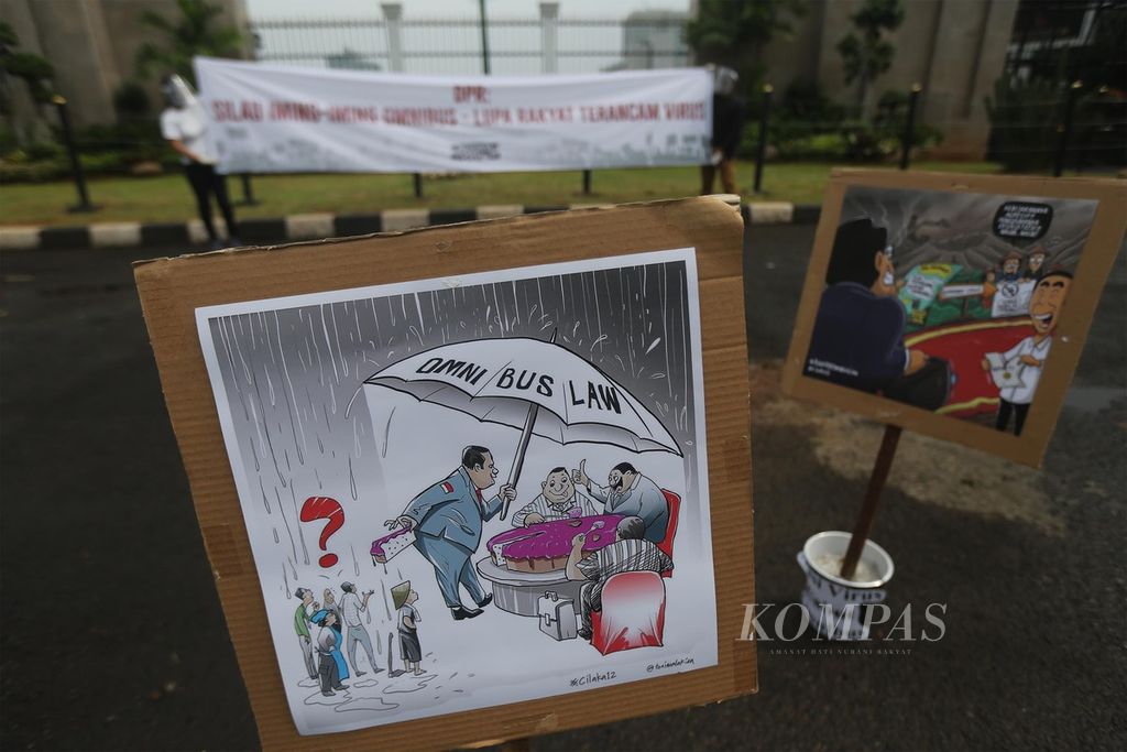 Gambar kartun berisi penolakan Rancangan Undang-Undang (RUU) Cipta Kerja dipasang oleh para aktivis dari gerakan #BersihkanIndonesia saat berunjukrasa di depan Gedung Parlemen, Jakarta, Selasa (14/7/2020). 