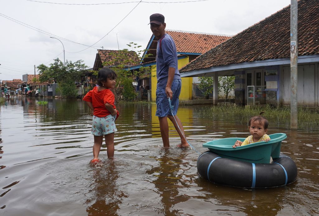Warga berjalan di tengah genangan banjir di Desa Mulyorejo, Kecamatan Tirto, Kabupaten Pekalongan, Jawa Tengah, Rabu (24/2/2021). Setelah tiga pekan, banjir di wilayah itu belum juga surut.