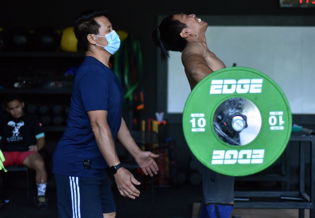 Lukman, pelatih angkat besi (kiri), mengawasi lifter nasional, Deni, saat latihan di Empire Fit Club, Stadion Gelora Bung Karno, Jakarta, Jumat (25/6/2021). Latihan itu dilakukan menjelang Olimpiade Tokyo 2020. Lukman kini menangani tim Thailand.