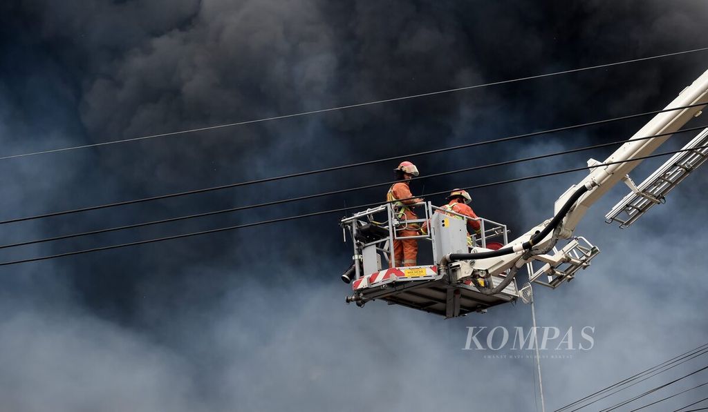 Petugas Dinas Pemadam Kebakaran dan Penyelamatan Kota Surabaya dengan <i>sky lift</i> berusaha memadamkan kebakaran gudang lampu di Jalan Kalianak, Surabaya, Jawa Timur, Jumat (9/9/2022). 