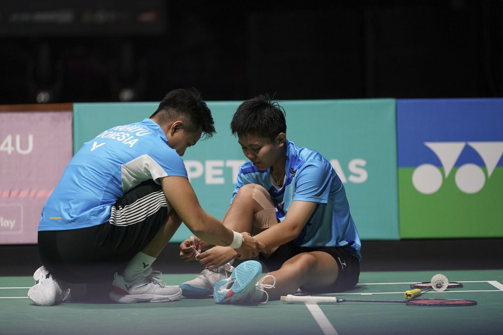 Apriyani Rahayu (kiri) membantu rekannya Siti Fadia Silva Ramadhanti yang mengalami cedera pergelangan kaki di tengah laga semifinal melawan pasangan China, Chen Qingchen/Jia Yifan pada turnamen bulu tangkis Malaysia Terbuka di Axiata Arena, Kuala Lumpur, Malaysia, Sabtu (14/1/2023). 