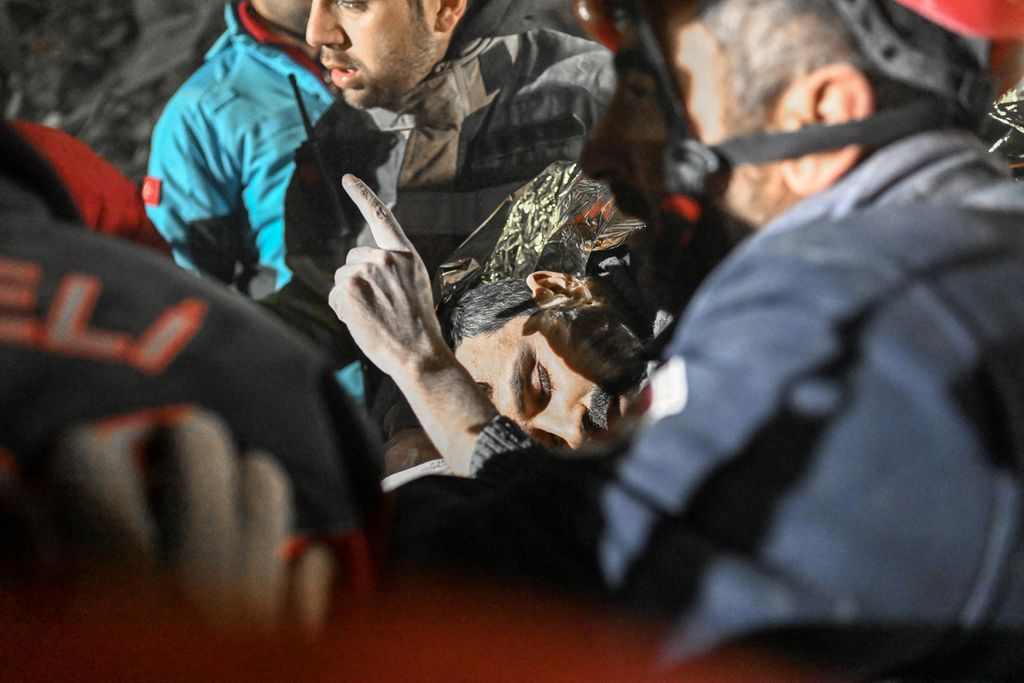 Warga Suriah, Faez Ghanam, mengacungkan jari telunjuknya saat dibawa ke mobil ambulan di Hatay, sisi tenggara Turki, Selasa (14/2/2023). Ia berhasil diselamatkan setelah terjebak di reruntuhan bangunan selama 210 jam. 