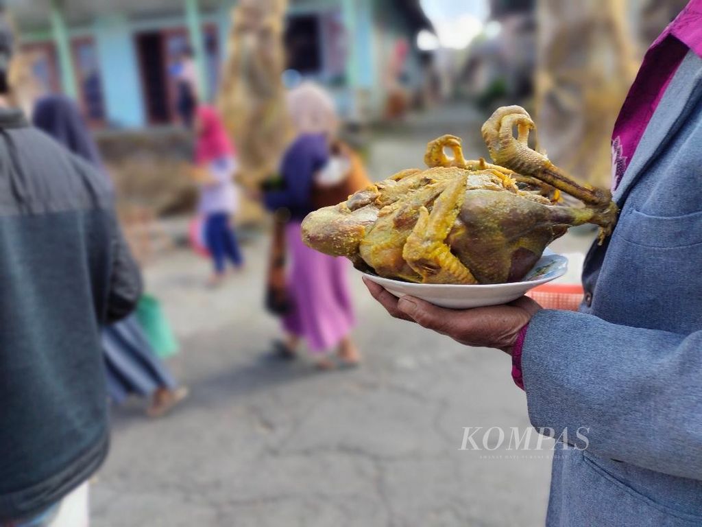 Ayam ingkung dibawa oleh seorang warga untuk diarak keliling kampung.