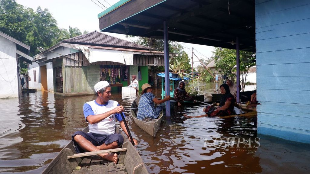 Warga bersantai dan mengobrol di beranda depan rumah warga yang terendam banjir di Kelurahan Sungai Lulut, Kecamatan Banjarmasin Timur, Kota Banjarmasin, Kalimantan Selatan, Minggu (24/1/2021). 