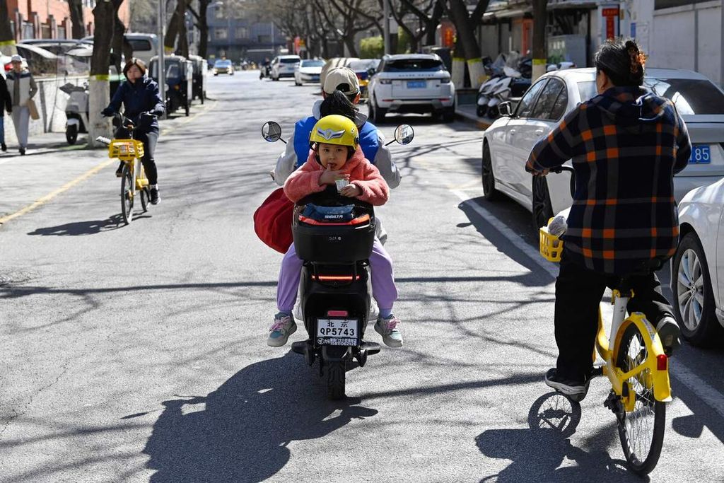 Anak-anak membonceng sepeda listrik di Beijing, China, 20 Maret 2024.