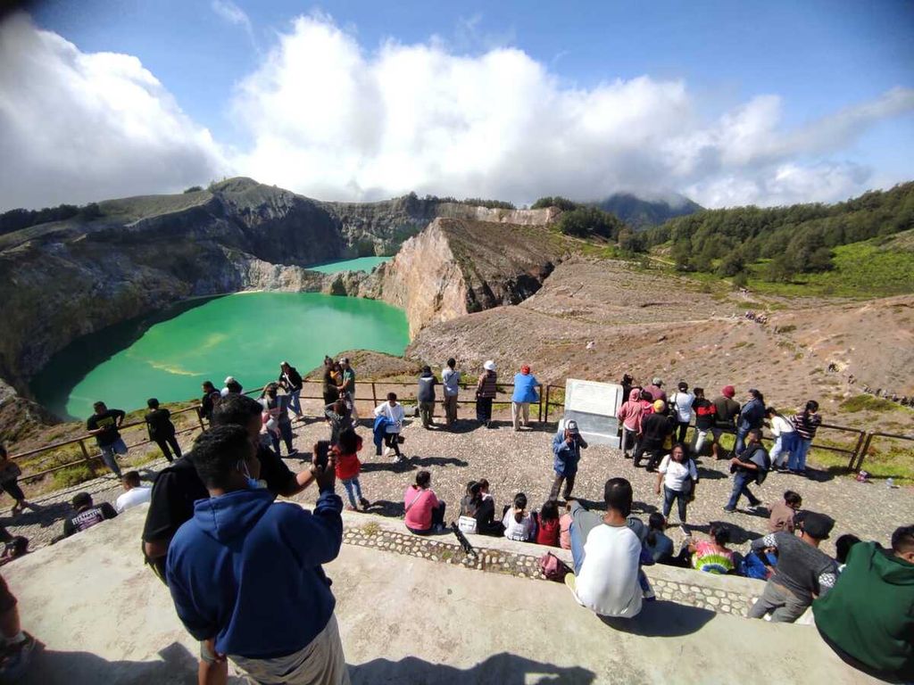 Pengunjung berekreasi di pelataran puncak Danau Kelimutu sambil menyaksikan keindahan tiga kawah danau masing-masing dengan tiga warna berbeda, yakni biru muda, hijau, dan hijau tua kecoklatan.