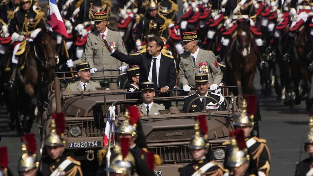 Presiden Perancis Emmanuel Macron melambaikan tangan saat dia berdiri di mobil komando yang melaju di jalan Champs-Elysees selama parade Hari Bastille. Hari Bastille adalah hari libur nasional Perancis untuk memperingati awal Revolusi Perancis pada 14 Juli 1789. 