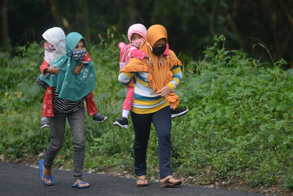 Ibu rumah tangga menggendong anak balita mereka menuju tempat pendidikan anak usia dini untuk memperoleh materi ajar non-daring di Desa Keditan, Ngablak, Magelang, Jawa Tengah, Selasa (21/7/2020). 
