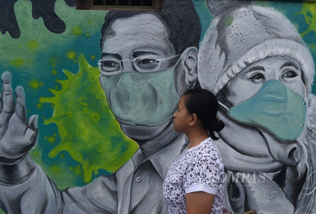 Warga melewati depan mural tema Pandemi Covid-19 yang dibuat Serikat Mural Surabaya di Jalan Stasiun Wonokromo, Surabaya, Jawa Timur, Kamis (4/2/2020). Kampanye mengenai bahaya dan cara pencegahan penyebaran Covid-19 dibuat di berbagai media salah satunya mural.