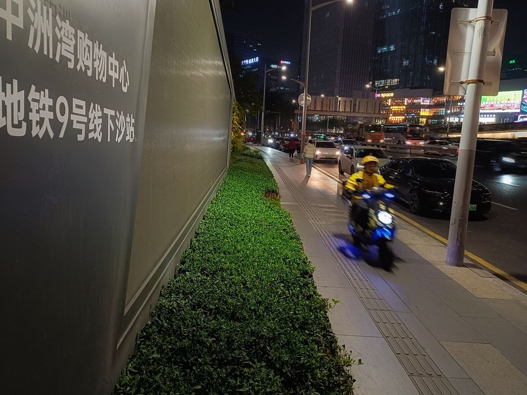 Pengendara sepeda motor listrik melintasi trotoar di salah satu pusat perbelanjaan di Shenzhen, Provinsi Guangdong, China, Rabu (20/12/2023). Sepeda motor listrik di kota ini dibolehkan melaju di atas trotoar.