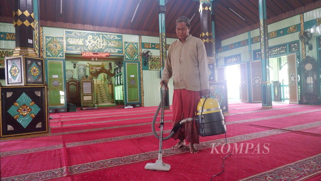Zainuddin (42), marbot masjid, membersihkan karpet masjid dengan alat penyedot debu di Masjid Bersejarah Sultan Suriansyah, Banjarmasin, Kalimantan Selatan, Senin (18/3/2024).