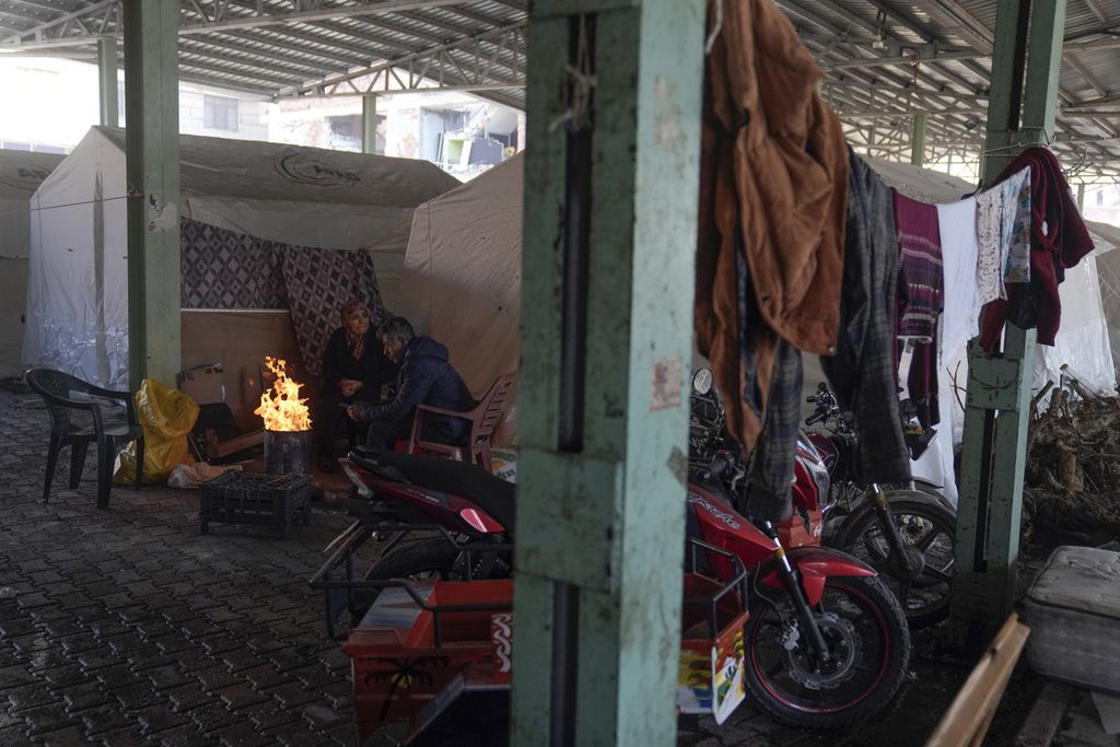 Pengungsi Suriah menghangatkan diri di depan perapian yang dibuat di depan tenda pengungsi di Distrik Islahiye di Gaziantep, Turki selatan, 11 Februari 2023. Rencana normalisasi hubungan Turki-Suriah membuka peluang bagi pemulangan atau repatriasi pengungsi Suriah yang ada di Turki. 
