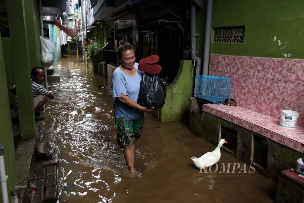 Warga membawa barang bawaan saat melintasi banjir di Kelurahan Kampung Melayu, Kecamatan Jatinegara, Jakarta Timur, Jumat (15/3/2024). Banjir yang melanda sejumlah daerah di DKI Jakarta perlahan mulai surut. 