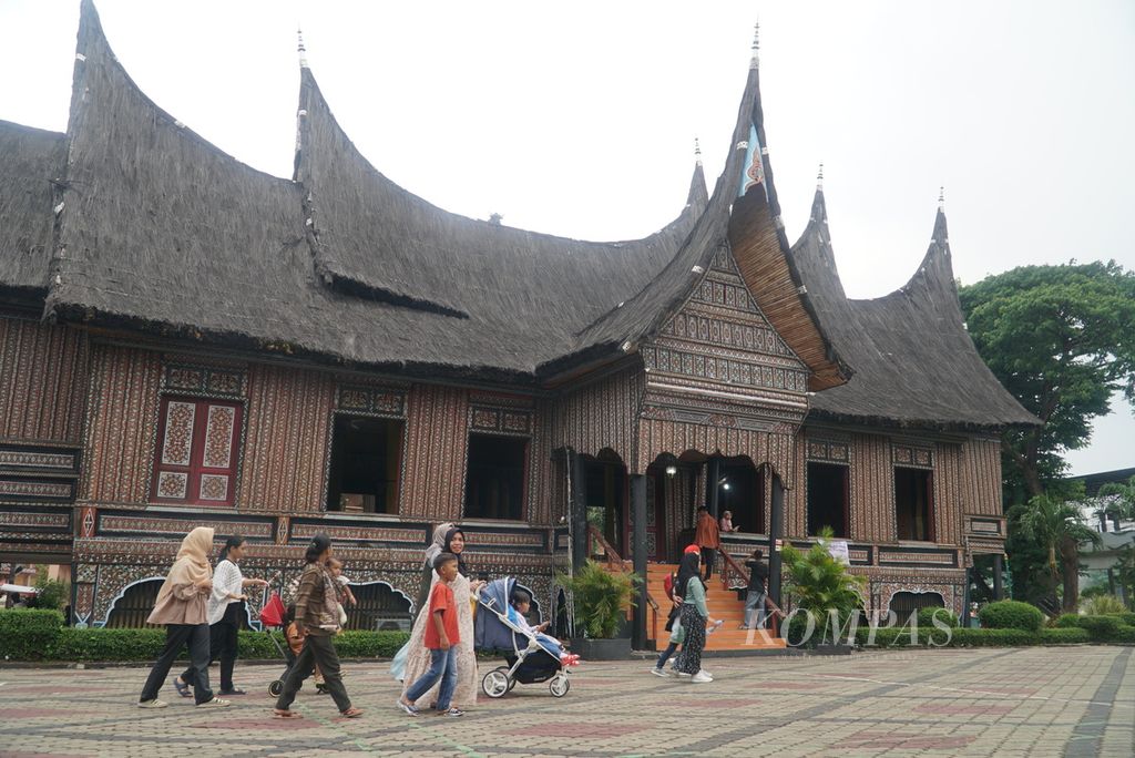 Wisatawan melintas di Rumah Gadang di Anjungan Provinsi Sumatera Barat di Taman Mini Indonesia Indah (TMII), Jakarta Timur, Senin (25/12/2023). Sekitar 20.000 orang berkunjung ke TMII pada libur Natal ini. Selain rekreasi, kunjungan ke lokasi ini juga sebagai wisata edukasi bagi anak-anak.