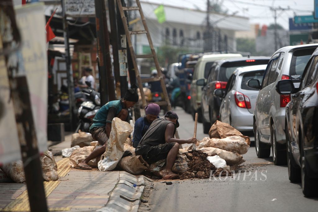 Pekerja menggali tanah untuk relokasi kabel utilitas yang tadinya di udara ke dalam tanah di Jalan Ceger Raya, Pondok Aren, Tangerang Selatan, Senin (18/9/2022). 