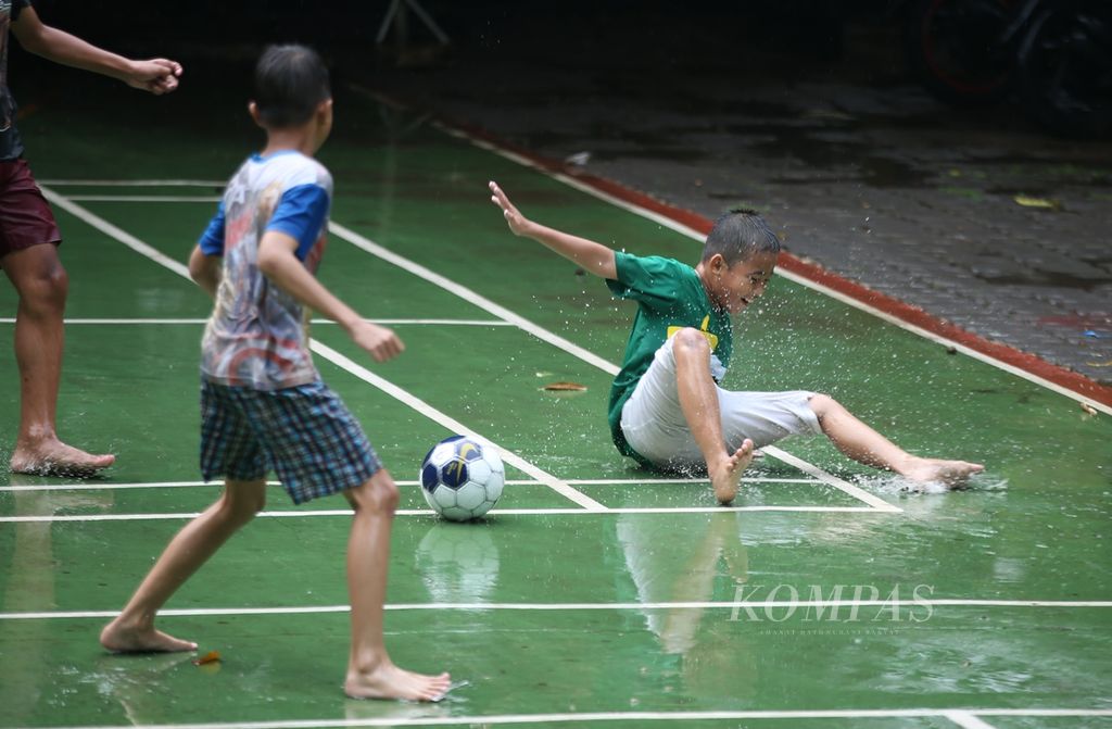 Para siswa SD Cilandak Barat 07 bermain bola saat hujan mengguyur kawasan Cilandak, Jakarta, Selasa (26/11/2019). Tidak seperti prediksi, Badan Meteorologi, Klimatologi, dan Geofisika memperkirakan musim hujan terlambat datang. 