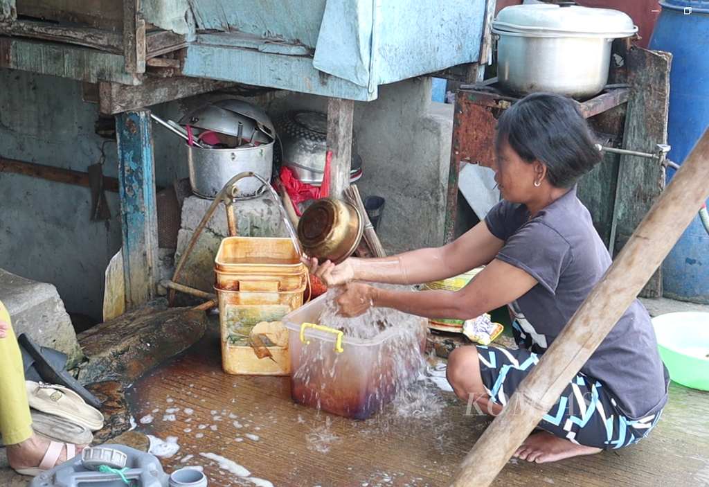 Seorang warga bantaran kali Ciliwung, Cideng, Gambir, Jakarta Pusat, sedang mencuci wadah plastik dengan air tanah, Senin (18/7/2023).
