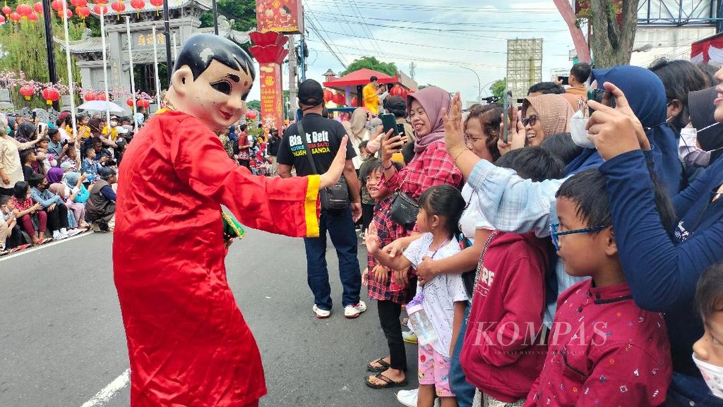 Salah satu penampil kirab memberi kesalam pada penonton di kawasan pecinan Kota Magelang, Jawa Tengah, Minggu (5/2/2023).