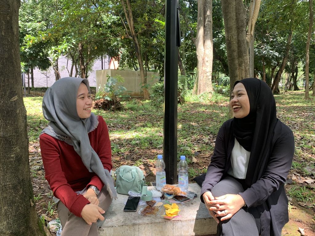 Nadiyah dan Siti duduk santai sembari menikmati kudapan di taman kota Gelora Bung Karno, Senayan, Jakarta, Minggu (23/10/2022). Mereka adalah warga Bekasi, Jawa Barat, yang mengunjungi Taman Hutan Kota GBK untuk sekadar rehat dari hiruk pikuk perkotaan.