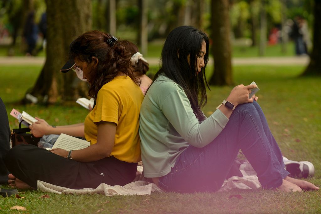 Dua warga membaca buku di kawasan Taman Lapangan Banteng, Jakarta Pusat, Sabtu (27/5/2023). 