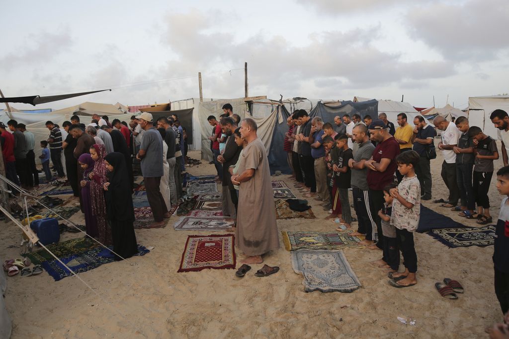 Warga Palestina yang mengungsi akibat serangan udara dan darat Israel di Jalur Gaza melaksanakan shalat Idul Adha di kamp tenda darurat Khan Younis, Gaza, Minggu (16/6/2024). 