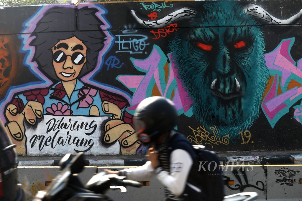 Mural yang ditambahi tulisan "dilarang melarang" tergambar di tembok jalan layang di Grogol, Jakarta, Jumat (15/11/2019). Mural ini menjadi sindiran terhadap RUU KUHP yang dianggap terlalu jauh dalam mengatur urusan pribadi warga negara. 