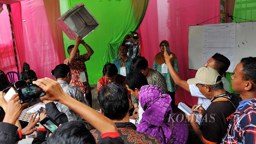 Anggota  Kelompok Penyelenggara Pemungutan Suara menunjukkan kotak suara yang telah kosong untuk memulai proses penghitungan suara dalam pemungutan suara ulang Pilkada DKI Jakarta 2017 di TPS 001 Utan Panjang, Kemayoran, Jakarta Pusat, Minggu (19/2). Dari 601 warga yang terdapat dalam daftar pemilih tetap, hanya 257 warga yang datang untuk memberikan hak suara pada pemungutan suara ulang tersebut.