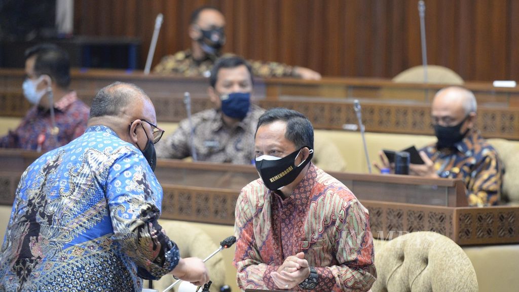 Menteri Dalam Negeri Tito Karnavian berbincang bersama anggota Komisi II DPR, Junimart Girsang, saat menghadiri rapat bersama Komisi II DPR untuk membahas pagu anggaran Kementerian Dalam Negeri 2021 di Kompleks Parlemen, Senayan, Jakarta, Senin (21/9/2020).
