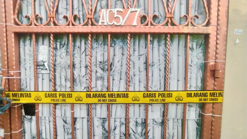 Garis polisi melintang di pagar besi rumah tempat ditemukannya empat mayat, Jumat (11/11/2022), di kompleks Citra Garden 1, Kecamatan Kalideres, Jakarta Barat.