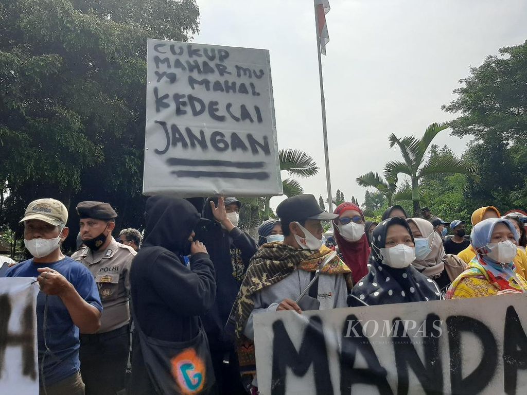 Sejumlah produsen tahu tempe berdiri dengan salah satu spanduk berisi seruan protesnya terhadap kenaikan harga kedelai di depan Kantor DPRD Kabupaten Magelang, Jumat (25/3/2022).