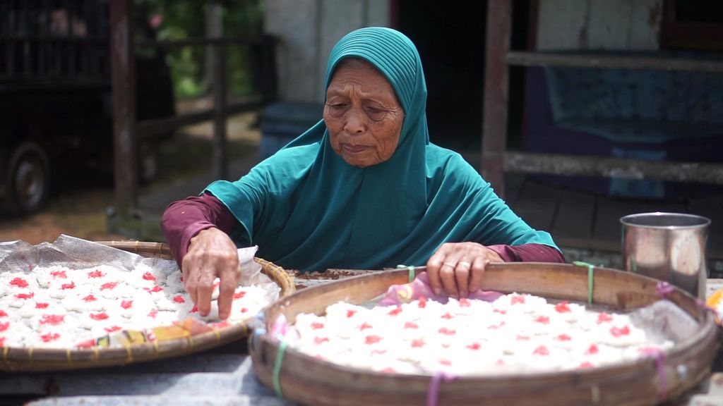 Tukinem (80), generasi pertama transmigran asal Pacitan, Jawa Timur, sedang menjemur rengginang yang ia buat sendiri di Desa Sukaraja, Kecamatan Sepaku, Penajam Paser Utara, Kalimantan Timur, Kamis (28/7/2022).