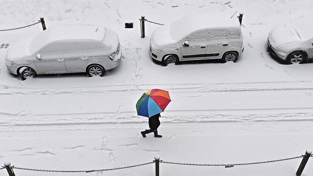 Seorang perempuan sambil menggunakan payung berjalan di tengah hujan salju, di Firenze, Italia, Kamis (1/3).  Badai salju melanda Eropa. Cuaca yang sangat dingin menyebabkan puluhan warga meninggal. 