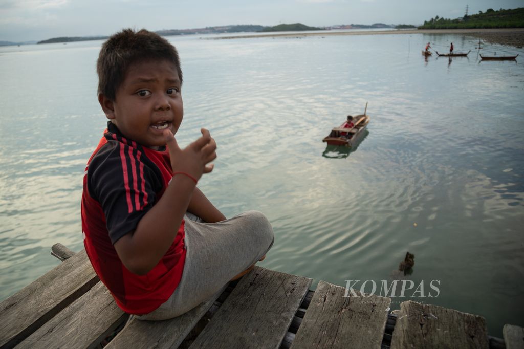 Seorang anak bermain di jembatan kayu tempat perahu berlabuh di Kampung Air Mas, Pulau Tanjung Sauh, Batam, Kepulauan Riau, Kamis (16/11/2023).
